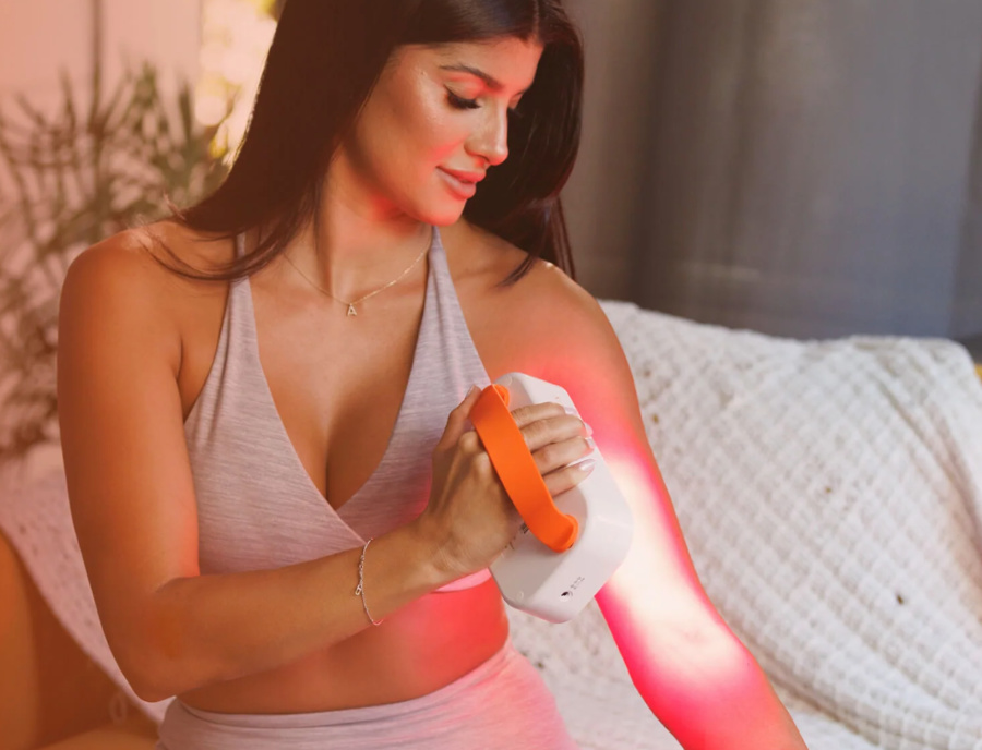 woman using red light therapy on her arm
