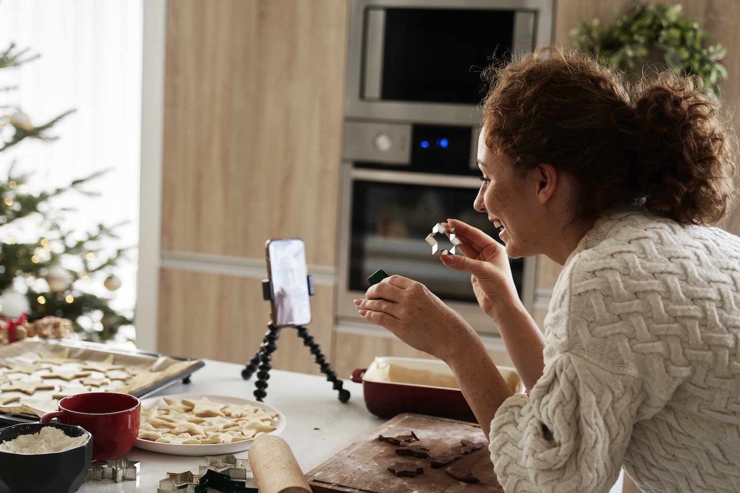 caucasian woman preparing gingerbread cookies and recording a video